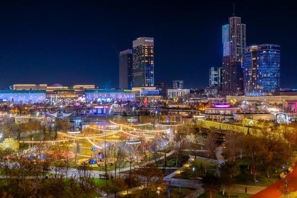 a night view of a city with tall buildings at Luxury 98m2, City Boulevard View, Fountain View, Tashkent City in Tashkent