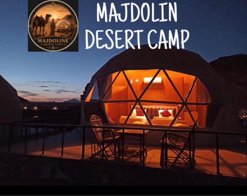 a tent with chairs and a table on a deck at MAJDOLINE Desert Camp in Wadi Rum