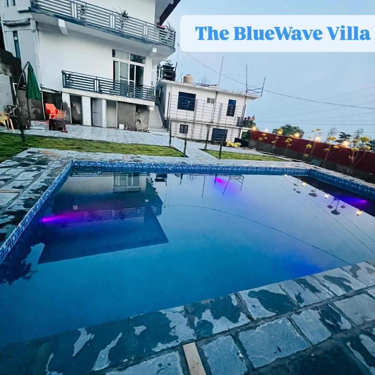 a swimming pool in front of a house at BlueWave Villa in Kangra