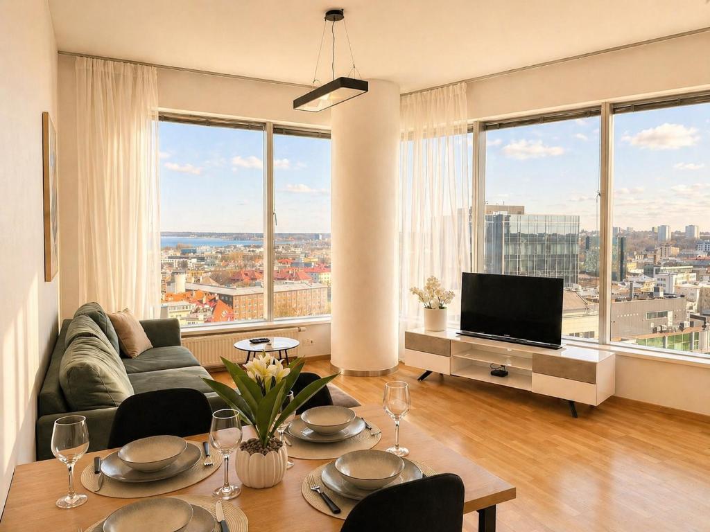 a living room with a table with chairs and a television at Panoramic Sea View - 12th floor in Tallinn