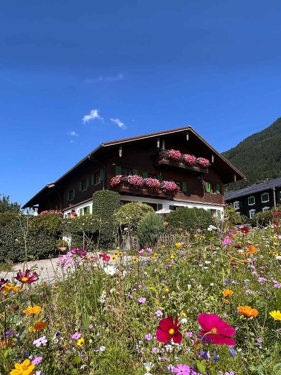 a building with a field of flowers in front of it at Ferienwohnungen Vogler in Oberstdorf