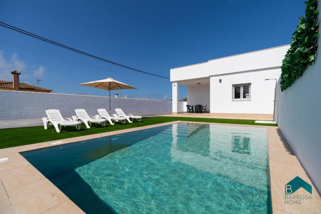 a swimming pool in front of a house at Ginebra B BARROSAHOME in Novo Sancti Petri