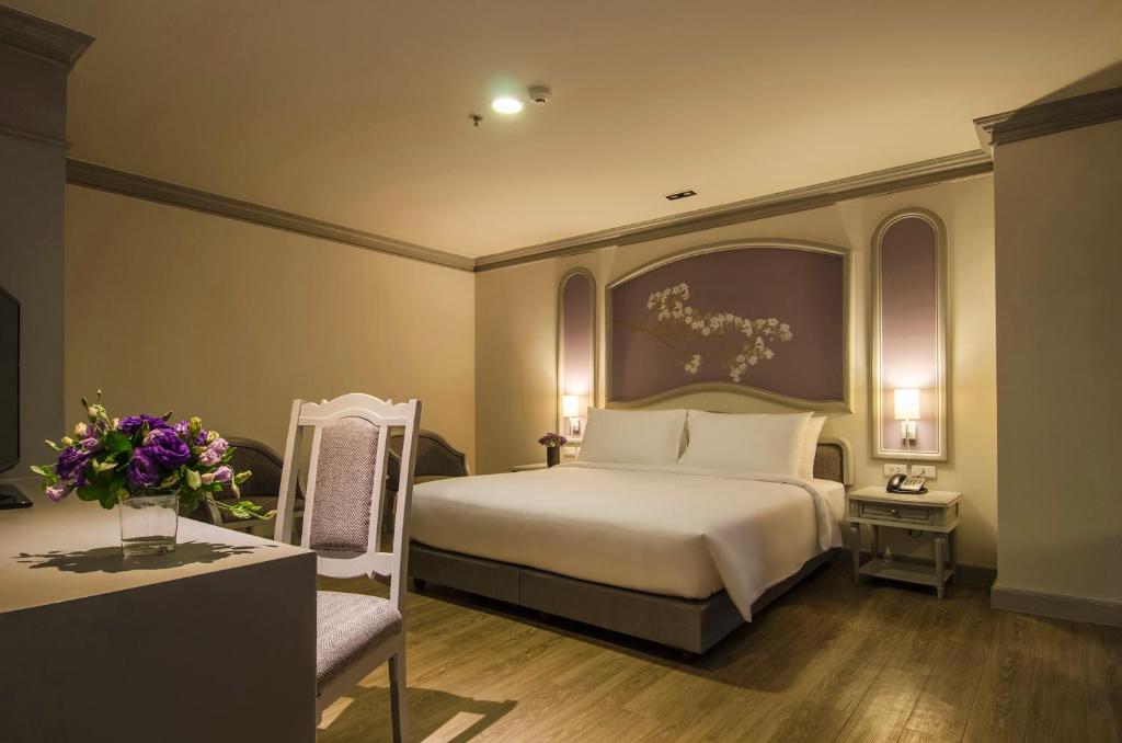 a bedroom with a bed and a chair and flowers at imm hotel Ladprao Bangkapi Bangkok in Bangkok