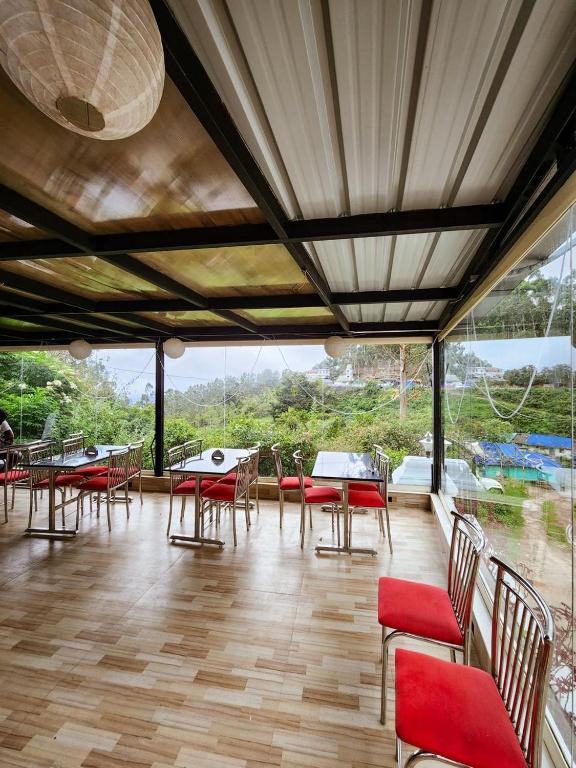 a dining room with tables and chairs and windows at Parudeesa Pool Resort in Vattavada