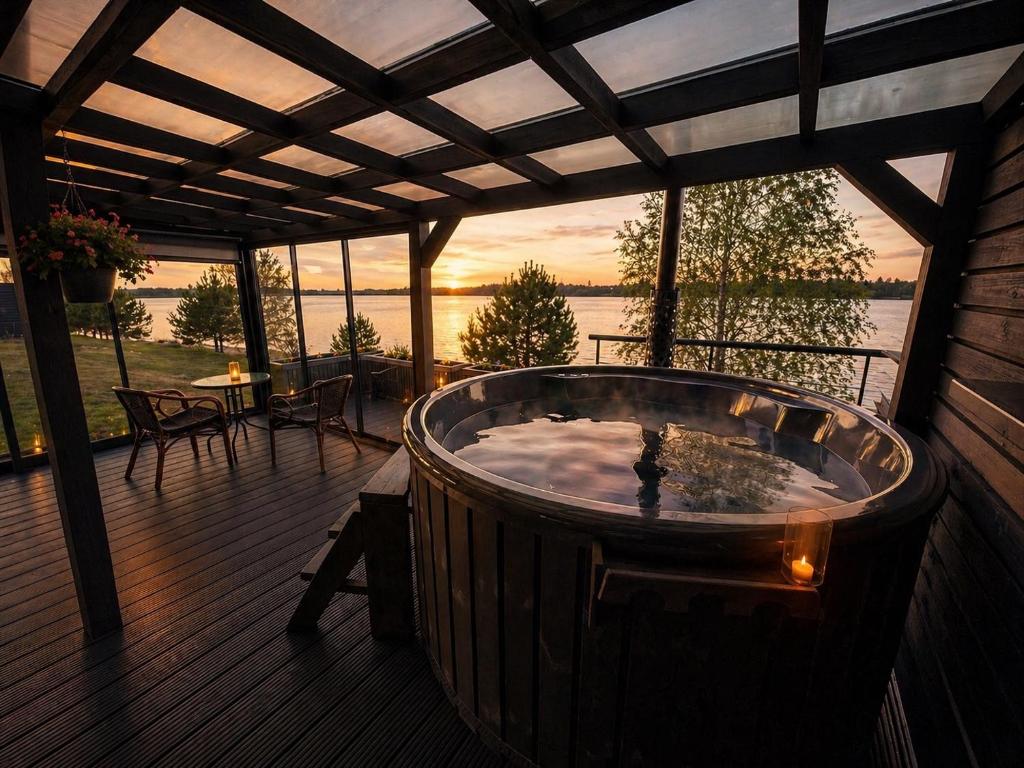 a hot tub on a deck with a view of the water at Doles skati, kubls - iekļauts cenā in Salaspils