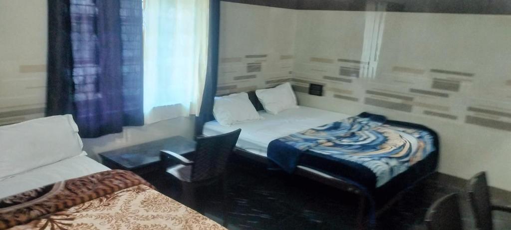 a bedroom with a bed and a chair and a window at Cmt Lodge & Rooms in Mysore