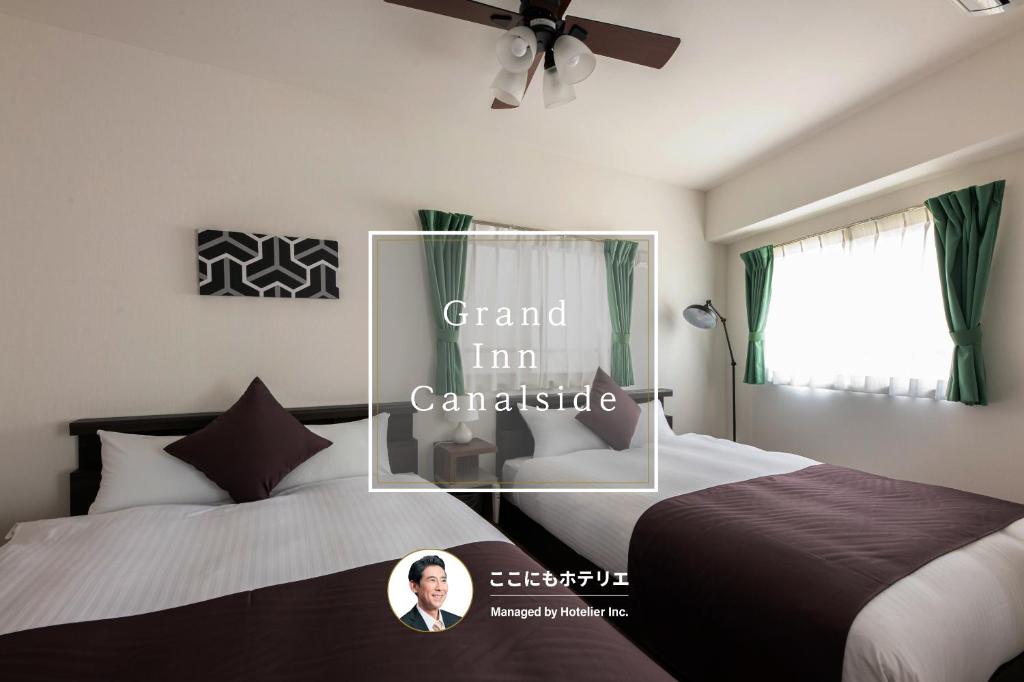 a bedroom with two beds and a mirror with the words grandi im canada at Grand Inn Canalside in Fukuoka