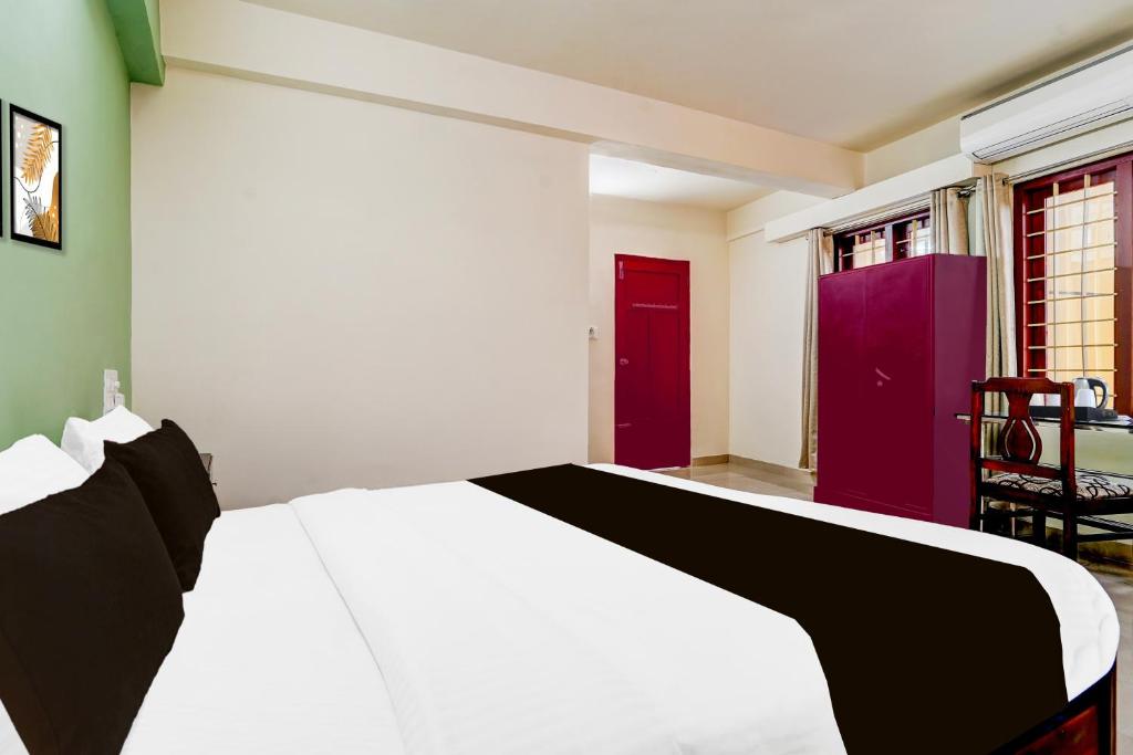 a bedroom with a white bed and a red door at Collection O Kottayam Formerly Sap Inn in Kottayam