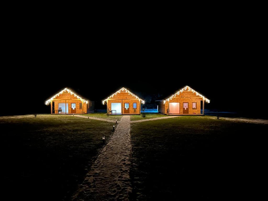 three wooden houses in a field at night at Chatka pod Stinskou in Zboj