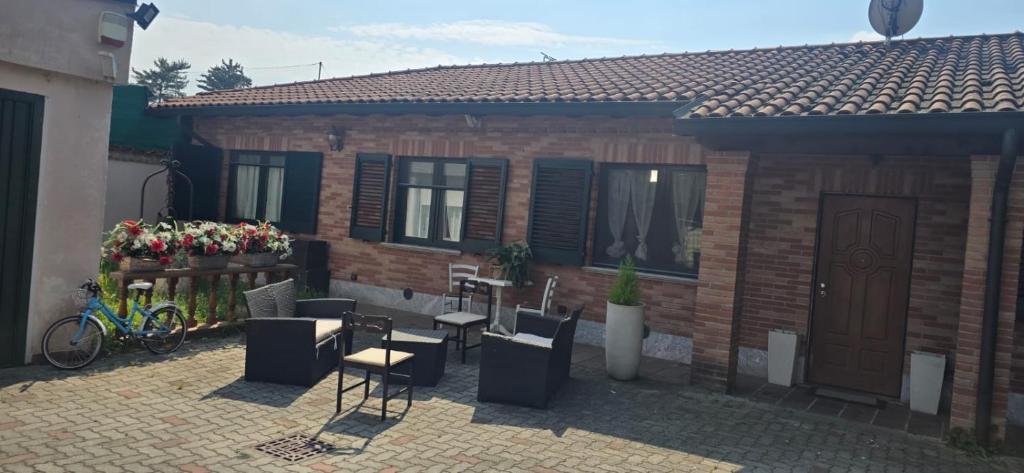a brick house with a patio with chairs and a table at Residenza dei pini lacchiarella in Lacchiarella