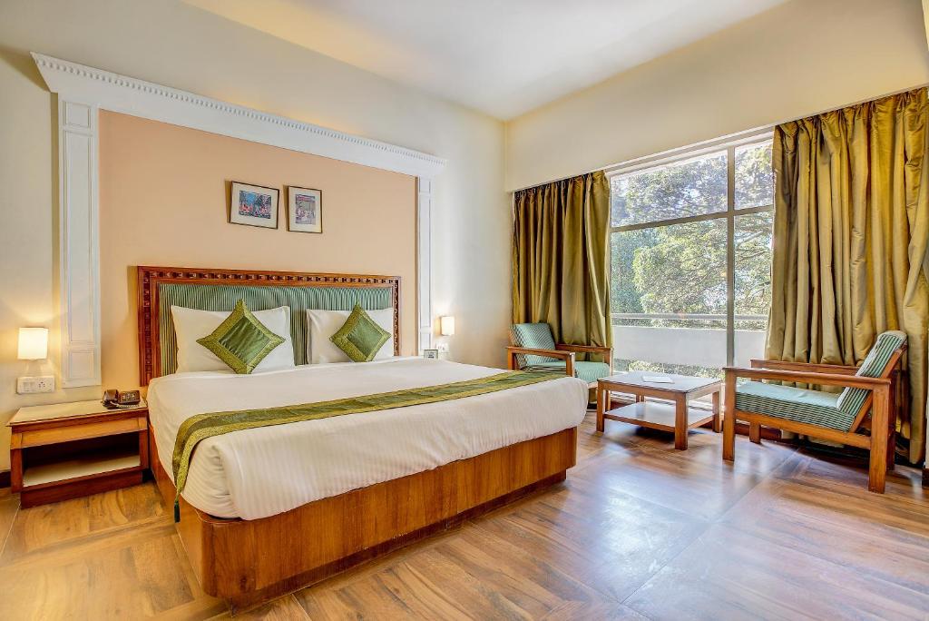 een slaapkamer met een groot bed en een groot raam bij Hotel Ajanta Continental in Dehradun