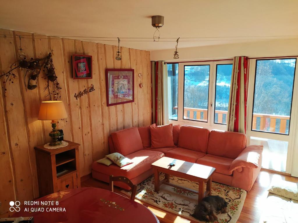 a living room with a red couch and a table at STOP mon grand F2 face au parc des Écrins in Orcières