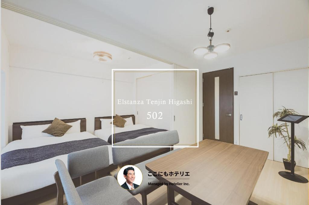 a woman sitting in a chair in a bedroom with a table at The HARBOR 天神東 in Fukuoka