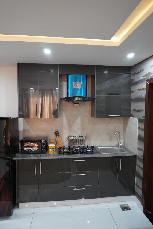 a kitchen with black cabinets and a sink at Eifel Heights Apartments in Lahore