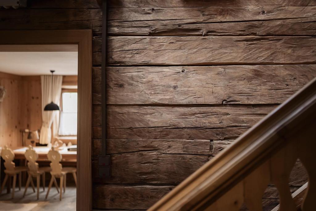 ein Zimmer mit einer Holzwand, an der ein Tisch und Stühle stehen in der Unterkunft Aussermahrhof - familyfarm in Gsies