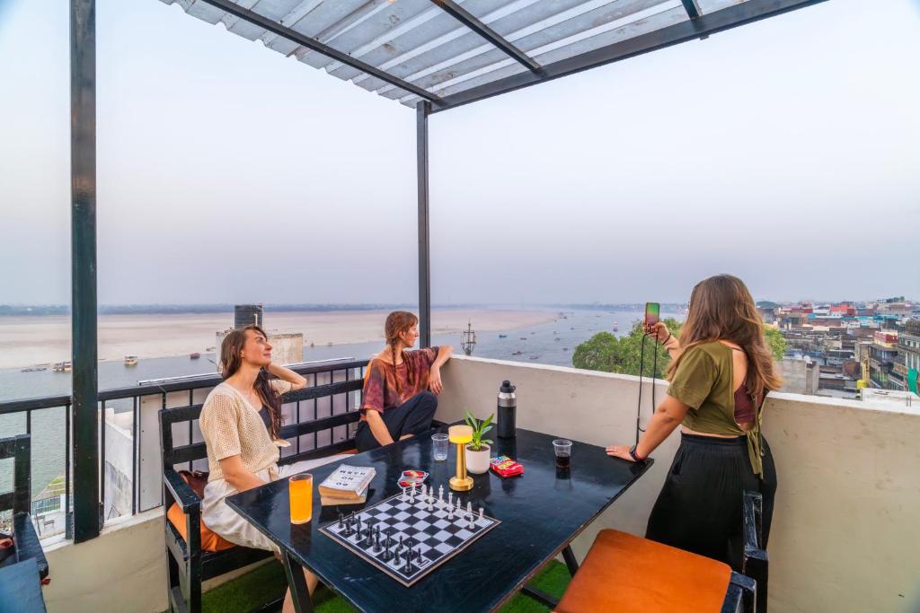 a group of people sitting at a table on a balcony at Madpackers Varanasi in Varanasi