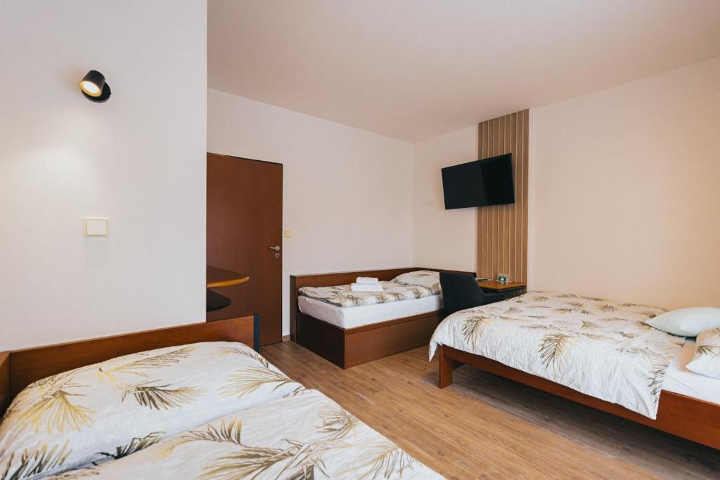 a hotel room with two beds and a flat screen tv at Penzion U Libuše Luleč in Lultsch