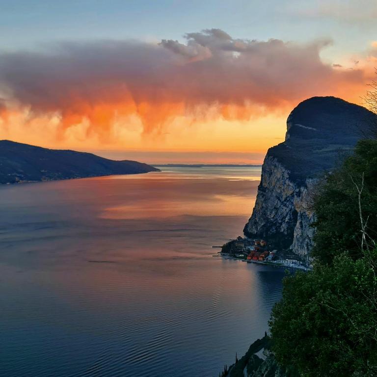 a sunset over the water with a large mountain at Appartamenti Fossato in Tremosine Sul Garda