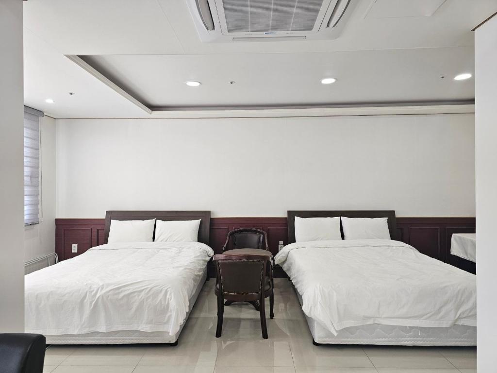 two beds with white sheets and a chair in a room at 인터시티365호텔 in Seoul