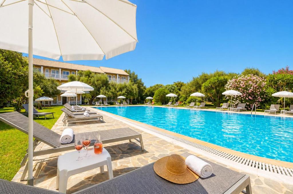 a pool with tables and umbrellas next to a building at Kosmas Apartments in Roda
