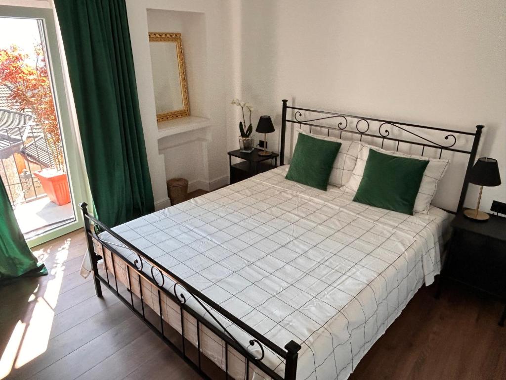 a bedroom with a bed with green pillows and a window at La dolce vita in Zelbio