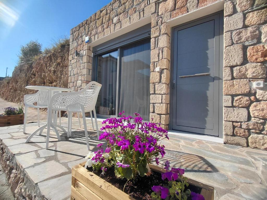 a patio with a table and chairs and purple flowers at Aqua villa Studio II in Elafonisos