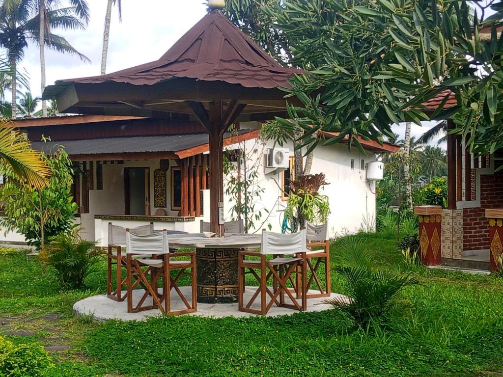a table and chairs in front of a house at Naicha Green in Tetebatu