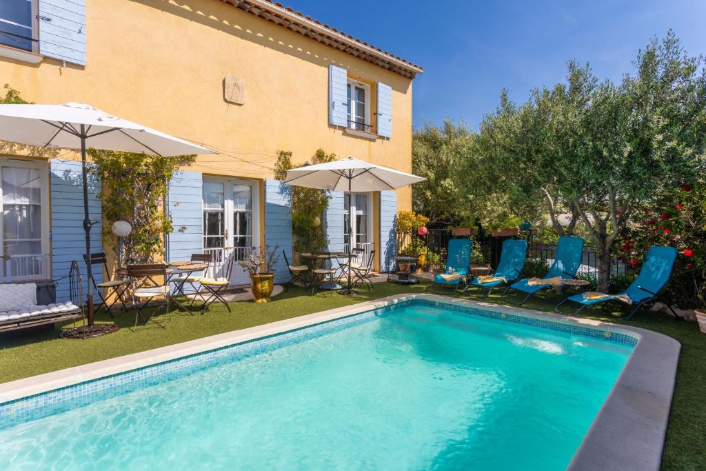 a swimming pool with chairs and umbrellas next to a house at Gite Chez Sophie in Roquebrune-sur-Argens