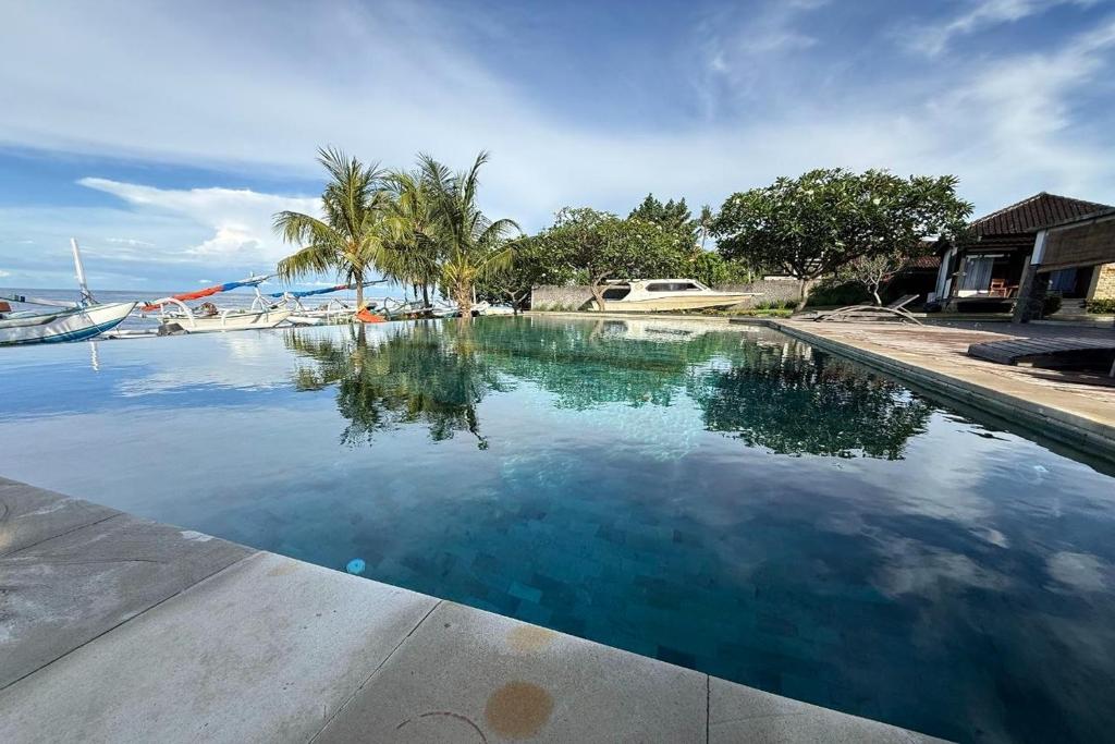 a pool of water with palm trees and a boat at Hi Blue Bali Melasti Dive Resort in Karangasem