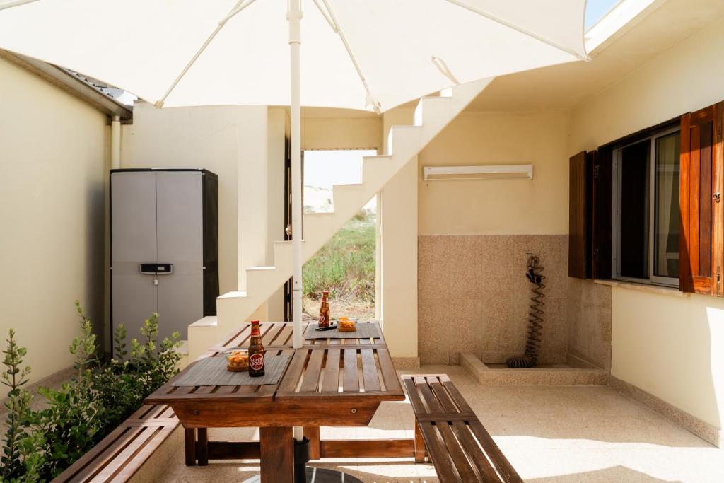 a patio with a wooden table and two benches at Casa da Areia - by RowdHouses - Private Beach Access in Praia da Barra