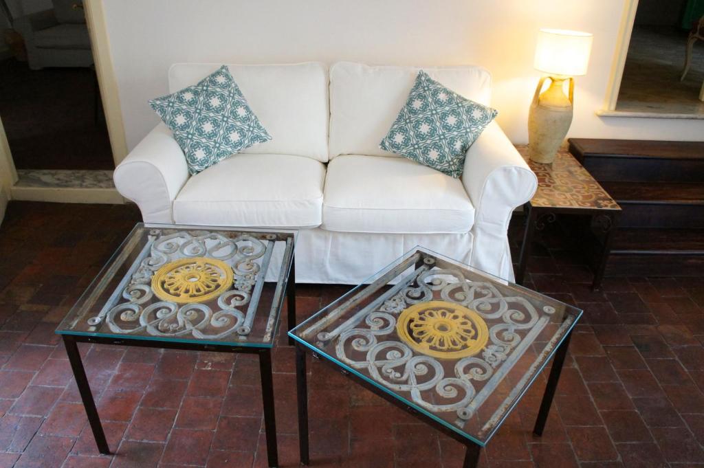 uma sala de estar com um sofá branco e duas mesas em Soffitta29 em Catânia
