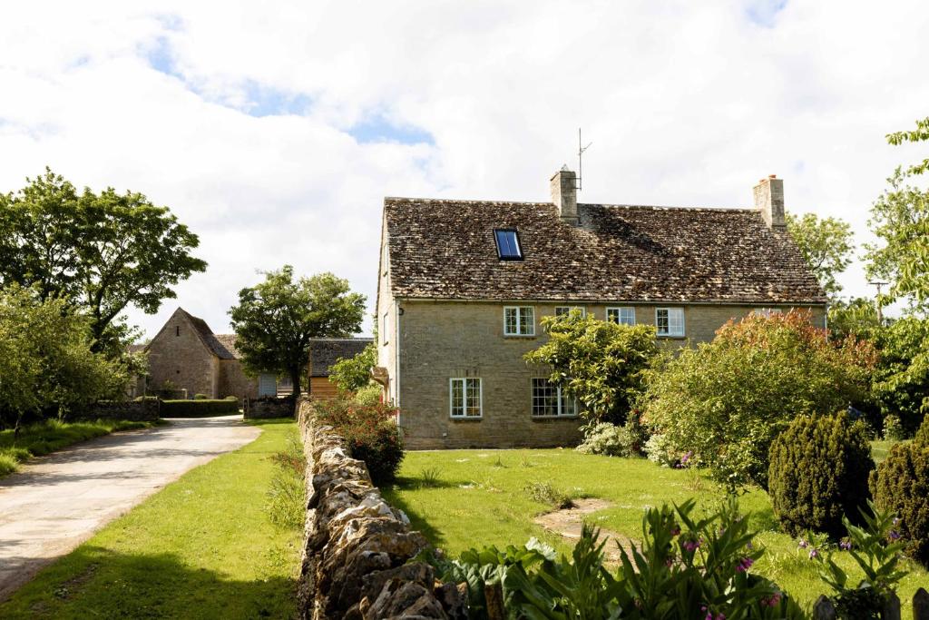 an old house with a stone wall next to a road at Stable Cottage in Lechlade
