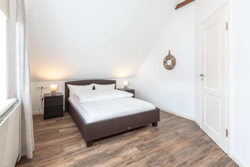 a white bedroom with a bed and two night stands at Ant Diekskant in Juist