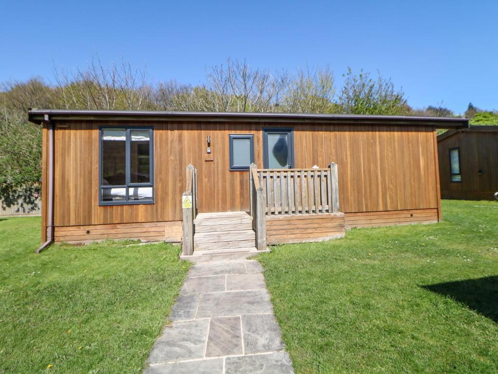 a small cabin with a bench in a yard at Dovestone Luxury Lodges sleeps 6 - pet free in Oldham
