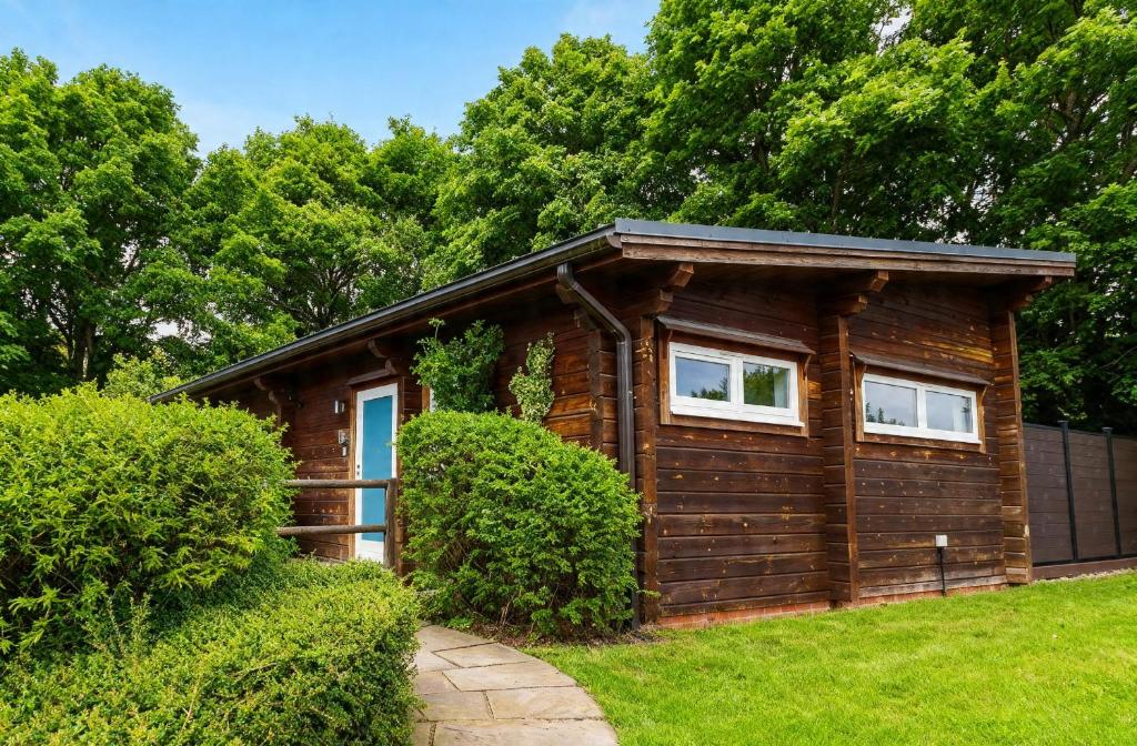 a log cabin with two windows in a yard at Pine Lodge Spa in Thirsk