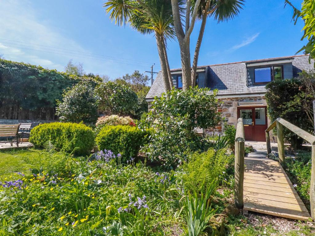 a house with a garden and a wooden walkway at Hydrangea Cottage in St Austell