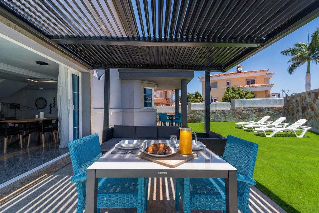 a patio with a white table and blue chairs at Villa Edén House by Maspalomas Holiday Villas in Maspalomas
