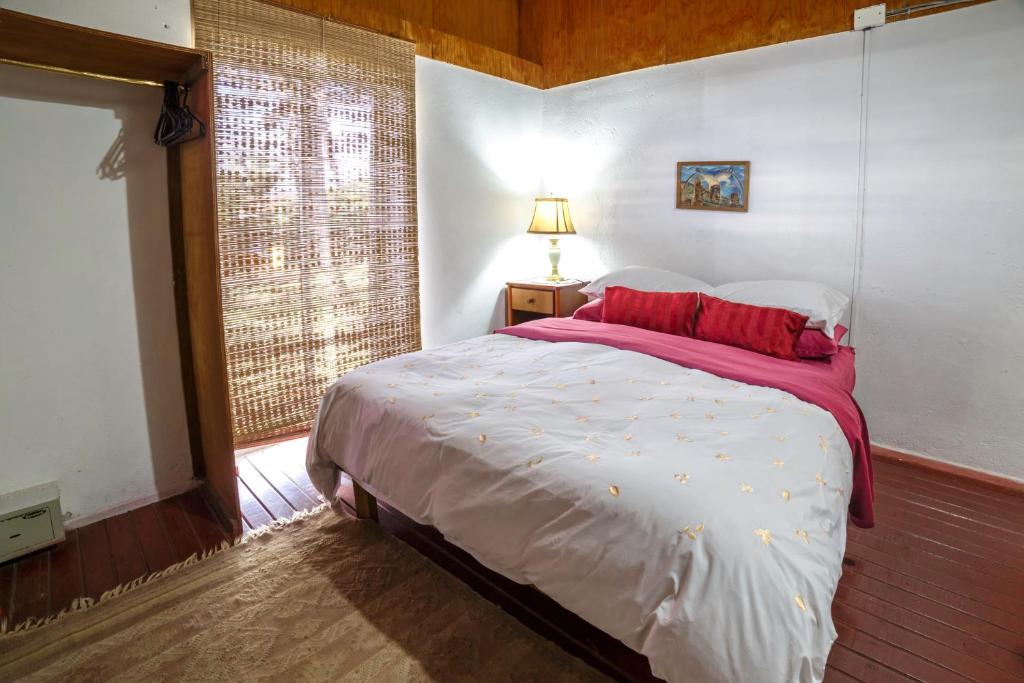 Un dormitorio con una cama con almohadas rojas y una ventana en Cabañas Matavai, en Hanga Roa