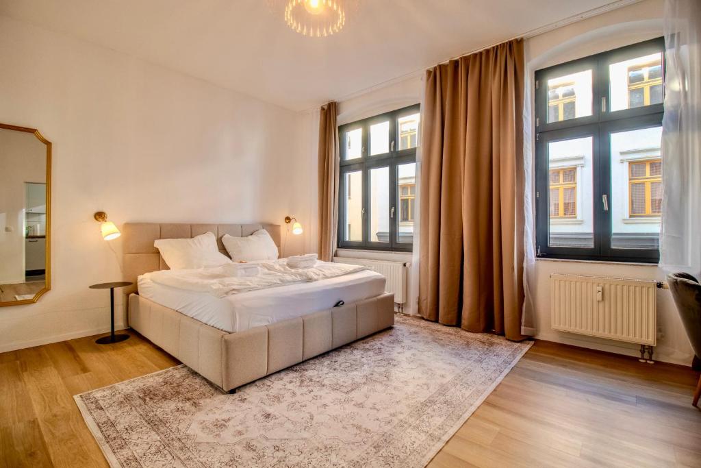 a bedroom with a white bed and two windows at Zentral & ruhig - Stadt, Elbe und Natur nebenan in Magdeburg