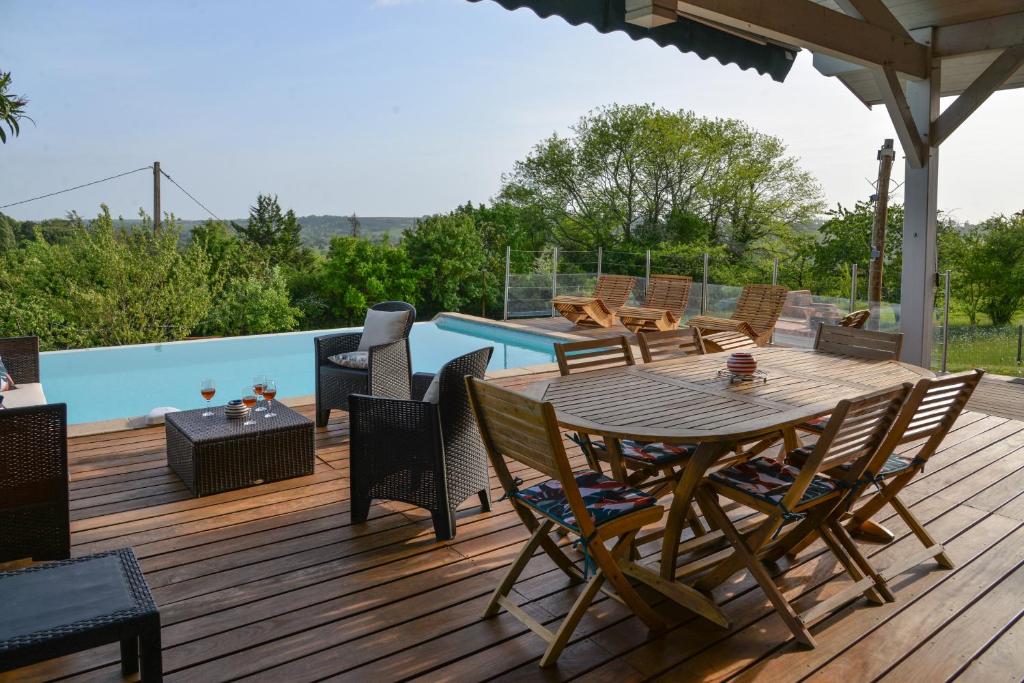 a deck with a table and chairs and a pool at Le Gite De La Colline in Nérac
