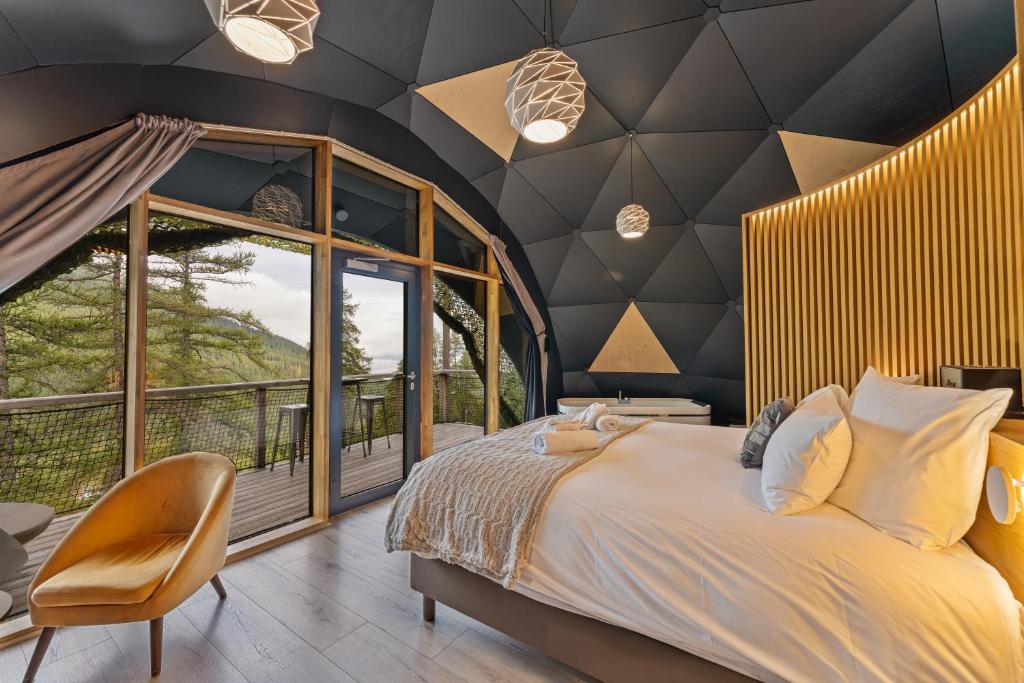 a bedroom with a large bed and a large window at Alpin D'Hôme Hôtel & Spa in Les Orres