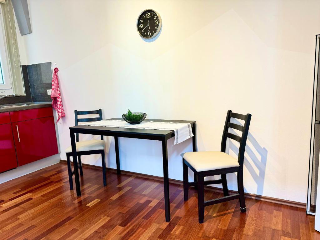 a dining room table with two chairs and a clock on the wall at Charmante Wg im Stadtgeflüster in Schwäbisch Hall