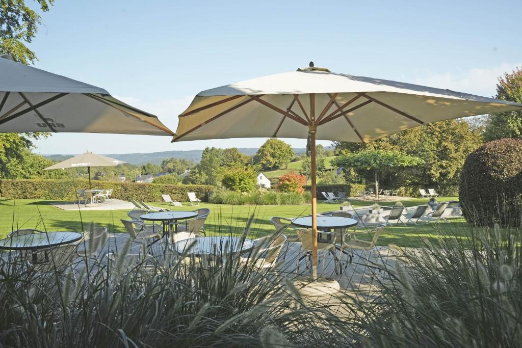 a group of tables and chairs under an umbrella at Hotel des Ardennes in Corbion