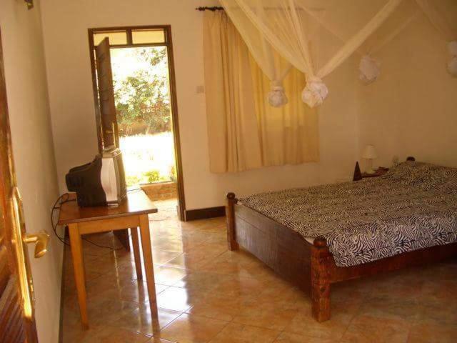 um quarto com uma cama e uma televisão em Mama Pierina Restaurant and Annex em Morogoro