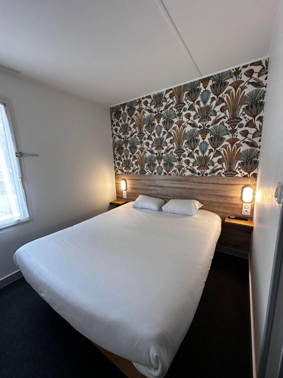 a bedroom with a large white bed with two pillows at Fasthotel Laval in Laval