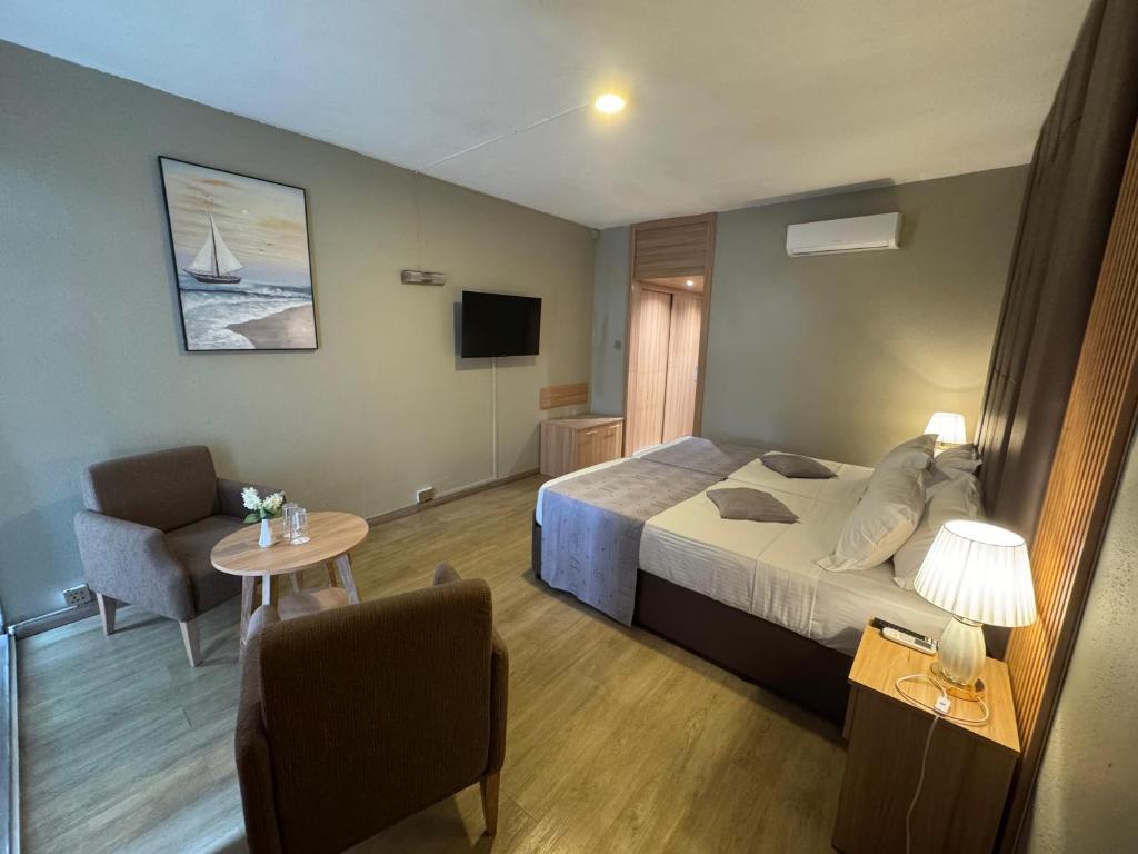 ein Schlafzimmer mit einem Bett, einem Tisch und einem Stuhl in der Unterkunft Gold Crest Hotel in Quatre Bornes