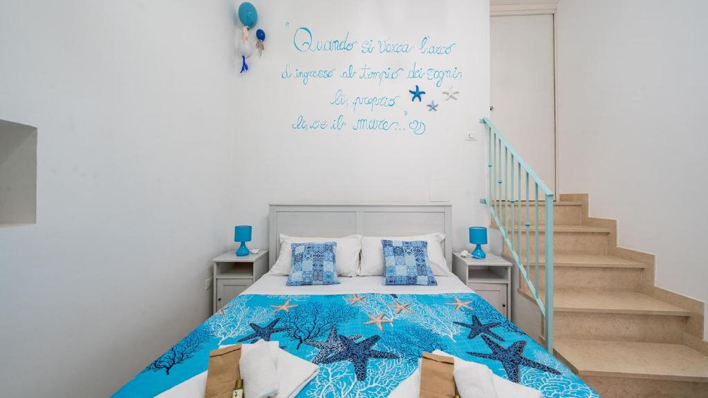 a bedroom with a bed with a blue comforter at La Casa Di Nicole by Rentbeat in Polignano a Mare