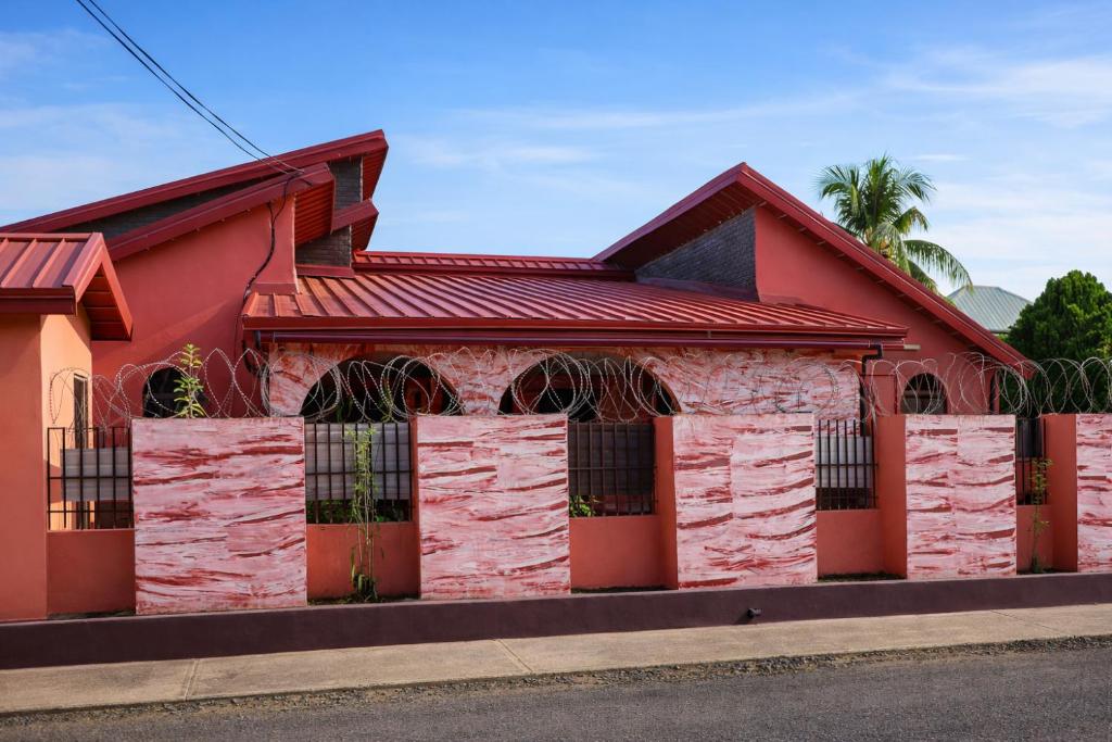 a red building with a fence in front of it at Rico Home Stay in Nkotunsi