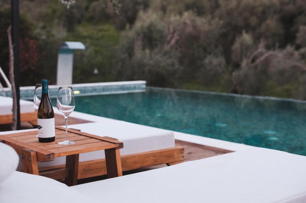 a bottle of wine and a glass on a table next to a pool at Azure Olive Collection in Ulcinj