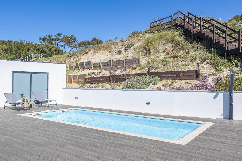 a house with a swimming pool next to a hill at Dunes Beach House with Ocean Views in Viana do Castelo